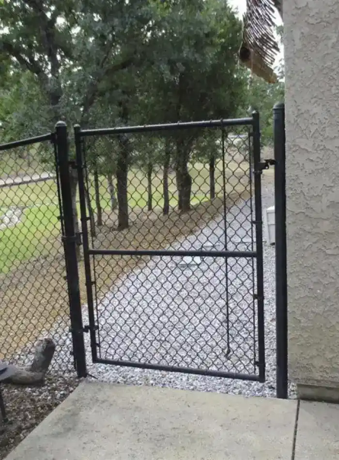 Metal chain-link gate properly connected to stucco wall as noncombustible fencing