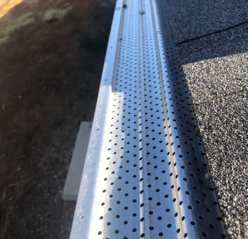Metal gutter guard installed on roof edge to prevent debris accumulation
